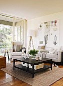 Black coffee table on sisal rug and sofa set with pale upholstery in modern living room