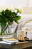 Teelichter in Birkenstamm und weiße Rosen auf Tisch