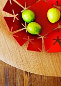 Lemons in red metal dish with perforated pattern on wooden surface