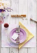 Romantische Tischdeko mit lilafarbenem Teller und gelber Serviette, Scrabble-Buchstaben und frühlingshaftem Blumenschmuck
