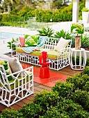 White garden sofas with orange side table on wooden terrace with retro flair by the pool