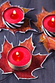 Painted autumn leaves used as coasters for tealights covered in washi tape