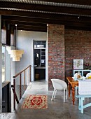 Dining area with various chairs and exposed brick wall on gallery with head of staircase