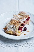 A slice of cherry strudel with icing sugar
