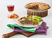 Slice of Traditional Tourtière - Canadian Meat Pie with greens and carrots