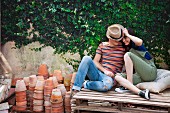 Young couple sitting on a wooden palette in a garden