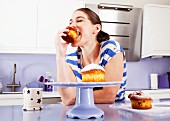 A woman biting into a muffin, with great enjoyment