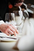 Kellner stellt leeres Weinglas auf den Restauranttisch