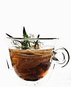 Chicken broth with celeriac in a glass cup against a white background