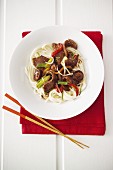 Japanese dish of beef with mushrooms and spring onions on a bed of noodles