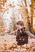 Caucasian boy playing in autumn leaves