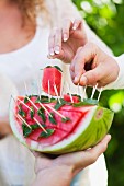 Gäste auf Gartenfest essen Wassermelone mit Spiesschen