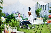 Junges Paar unterhält sich beim Sommerfest im Garten