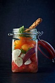 A jar filled with duck, melon, tomatoes and mozzarella