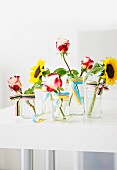 Einzelne Sonnenblumen & Rosen in Glasvasen mit Bändern dekoriert