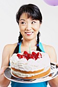Asian woman holding cake with candle