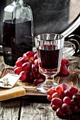 Vintage glass of red wine with bnch of red grapes and cheese