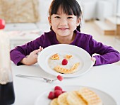 Chinese girl making a face on plate with waffle