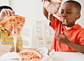 Zwei Kinder essen Pizza