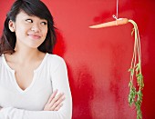 Asiatische Frau steht neben aufgehängter Karotte