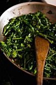 Broccolini being fried in a pan