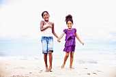 Two dark-skinned girls standing on beach hand in hand
