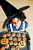 A little witch with Halloween biscuits