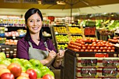 Asian woman working in produce section of grocery store