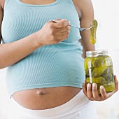 Schwangere Frau mit einem Glas Essiggurken
