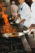 Koch flambiert Gericht in der Pfanne