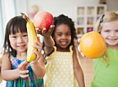Kindergartenkinder zeigen frische Früchte