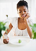 Frustrated Black woman looking at brussels sprout