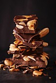 Several chunks of chocolate with nuts and almonds, stacked