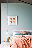 Bett mit Plaid und Kissen vor Wand in pastellfarbenem Türkis mit Masking Tape, minimalistische Pendelleuchte