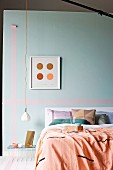 Blanket and cushions on bed against pastel turquoise wall with washi tape stripes and minimalist pendant lamp