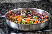 Carrots with red cabbage, broccoli and onions in a frying pan