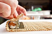 Maki sushi being rolled up using a bamboo mat