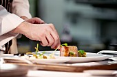 Chef plating up pork dish during service at working restaurant