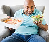 Mann wählt zwischen einer Pizza und Salat