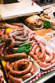 Various types of sausages and meat in a display in a butcher's shop
