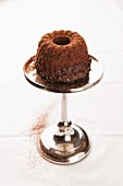 A chocolate Bundt cake on a silver cake stand