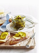 Bread and butter pickles (pickled gherkins with mustard and vinegar) in preserving jar and on slice of bread