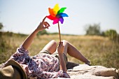 Frau auf Decke liegend mit buntem Windrad in der Hand