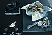 Minimalist table arrangement in charcoal - iced oysters in crumpled-effect dish on table top painted with blackboard paint