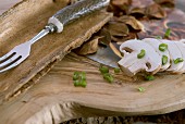 Sliced mushrooms and spring onions on wooden board; rustic fork with horn handle in bark dish