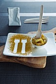 Fork prints in curry powder on a plate with a bowl of curried potatoes