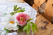 Two peony flowers in small basket decorating rustic wooden table