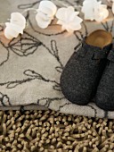 Lichtergirlande und Filzpantoffel auf gemusterter Decke und Hochflor-Teppich