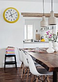 Dining area in mixture of styles - classic chairs at rustic walnut table and yellow-framed station clock next to hatch