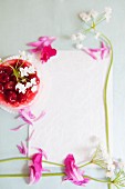 Raspberry jelly and flowers decorating the edge of a piece of paper